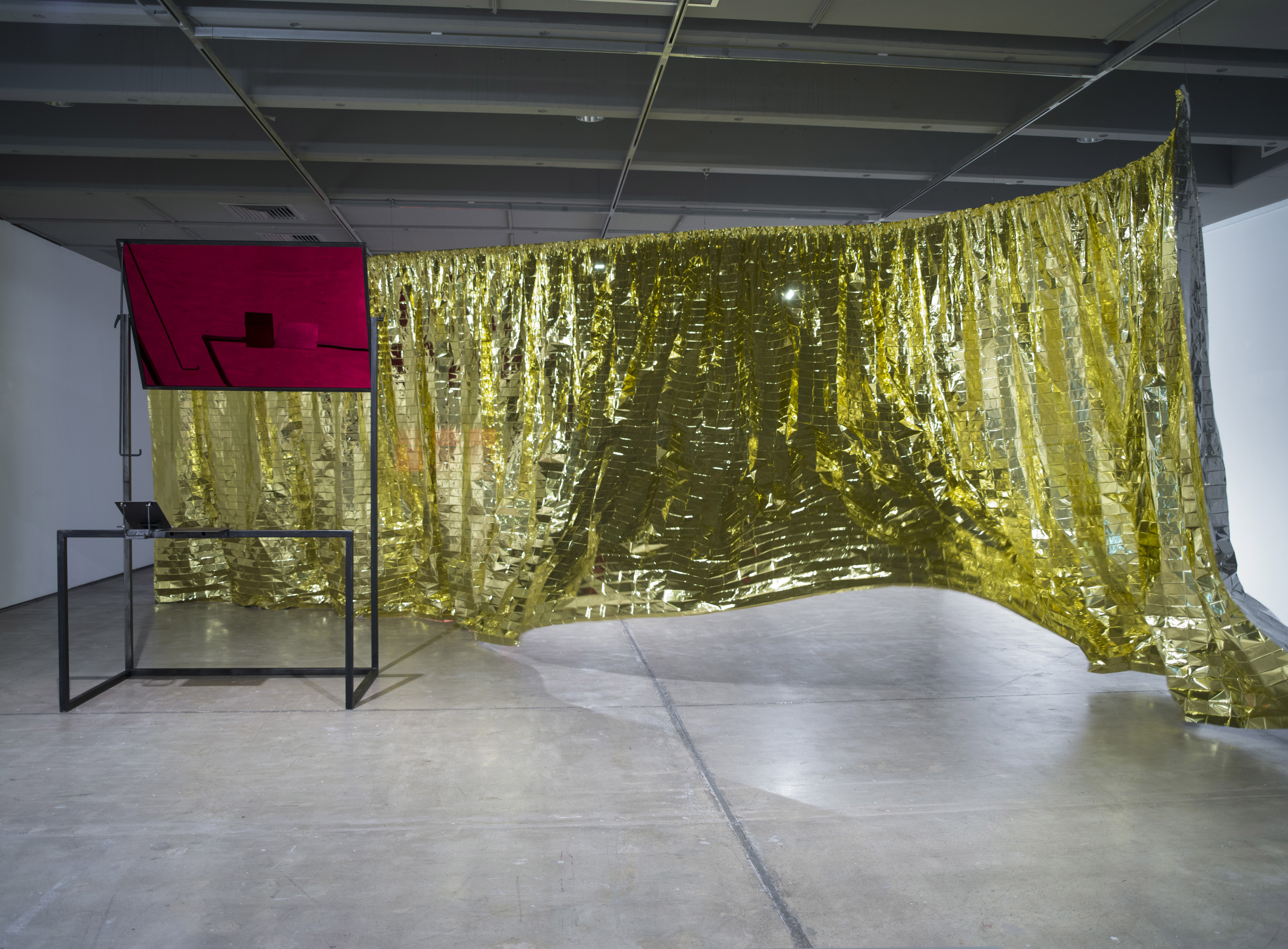 Céline Condorelli. Installation view. Study for Additionals (Structure for Public Speaking) (2012). Materials: Mild steel, perspex, mirror film Dimensions: 160 × 120 × 230cm. Structure for Communicating with Wind, from the series Additionals (2012-2013) Metallicised space blanket, curtain tape, fan. Image courtesy the artist. Photo: Carl Warner